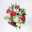 A hand-tied bouquet viewed from above, filled with crimson roses, pink-red carnations, and snowy white daisies, looks as bright and welcoming as a sunny morning on Greenford Broadway. The roses sit at the heart of the design, their velvety petals spiralling open in rich shades of deep red, while the carnations curl around them in softer, ruffled tones, almost feather-like at the edges. Clusters of tiny white chrysanthemums and gypsophila, or baby's breath, spill gently between the larger blooms, creating a light, cloudlike halo that softens the intense reds. Eucalyptus stems arc through the bouquet, their round, silvery-green leaves catching the light and adding a cool, contemporary twist against the deeper tropical foliage beneath. The greens are glossy and confident, shaping the bouquet into a neat, rounded dome that feels both polished and relaxed, as if it has just been gathered from a well-loved garden off Oldfield Lane. The lighting is natural and gentle, highlighting the texture of each petal - the slight sheen of the rose, the velvet ruffles of the carnation, the daisy-fresh simplicity of the white blooms. This is a celebratory arrangement, perfect for a birthday tea in a Greenford living room, a warm welcome home, or a quiet congratulations shared over coffee. You can almost imagine resting it on a hallway table, where its fragrance greets you like a friendly neighbour, filling the space with an uplifting, affectionate energy that lingers long after the first glimpse.