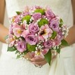 Radiant with soft light and joy, this Greenford bridal bouquet harmonises gentle lilac roses, rosy alstroemeria, and lively green button mums in a celebration of colour and texture. The sumptuous roses unfold with a delicate scent, embodying both tradition and the freshness of an English late spring. Among them, feathery sprays of white baby's breath float like clouds, enriching the bouquet with a sense of gentle airiness and innocence. The crisp vibrance of the lime green chrysanthemums lends a sophisticated pop, referencing modern trends seen in Greenford's stylish weddings. Deep green leaves arc gracefully, cradling the bouquet as the bride's hands rest in quiet anticipation, the soft white of her dress gleaming behind. Finished with local care and artistry, this arrangement feels made for cherished moments in the neighbourhood-whether at a celebration in Greenford's parks or a gathering with loved ones. Its serene glow and youthful energy make it perfect for capturing the spirit of new beginnings and heartfelt ceremonies in the heart of Greenford.